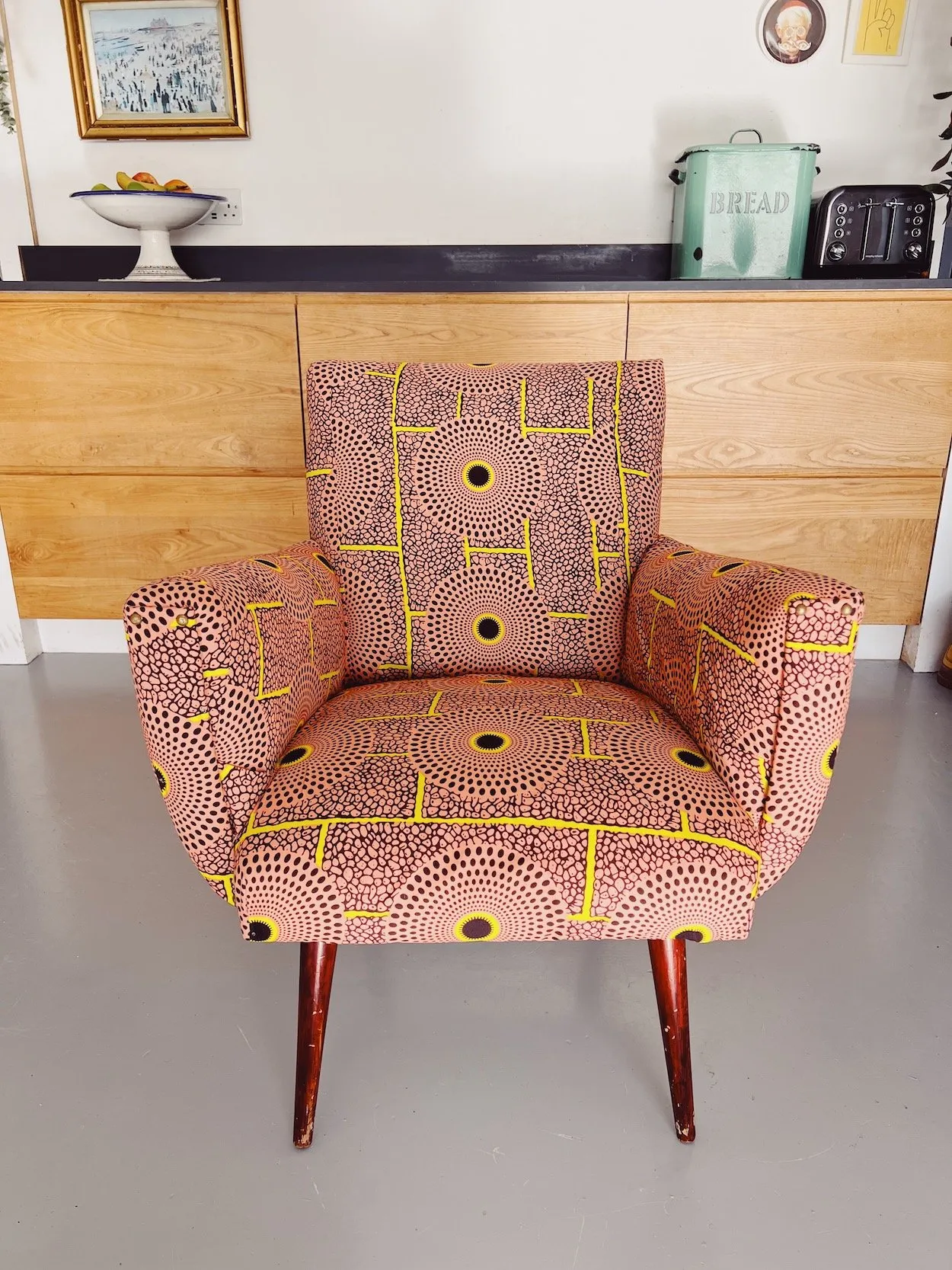 A mid-century armchair reupholstered in a pink and yellow print